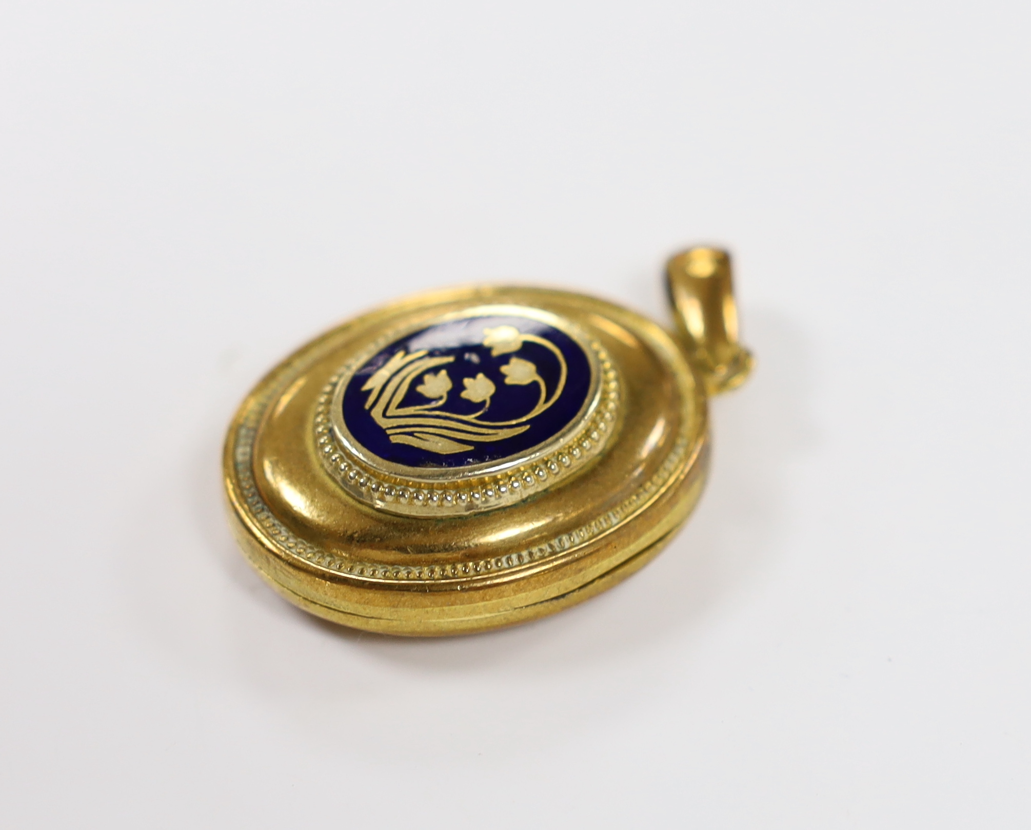 An early 20th century gilt metal and blue enamel set oval locket, with floral motif, overall 48mm, gross weight 17.3 grams.